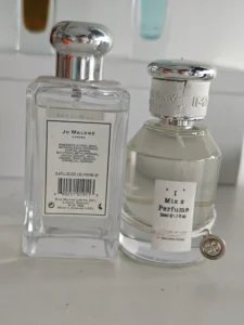 Cost structure comparison showing a luxury English Pear and Freesia cologne next to a long-lasting factory direct parfum alternative.