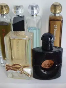 Side-by-side comparison of a luxury YSL Black Opium bottle and a long-lasting perfume dupe, highlighting the difference between brand markup and raw fragrance oil quality.